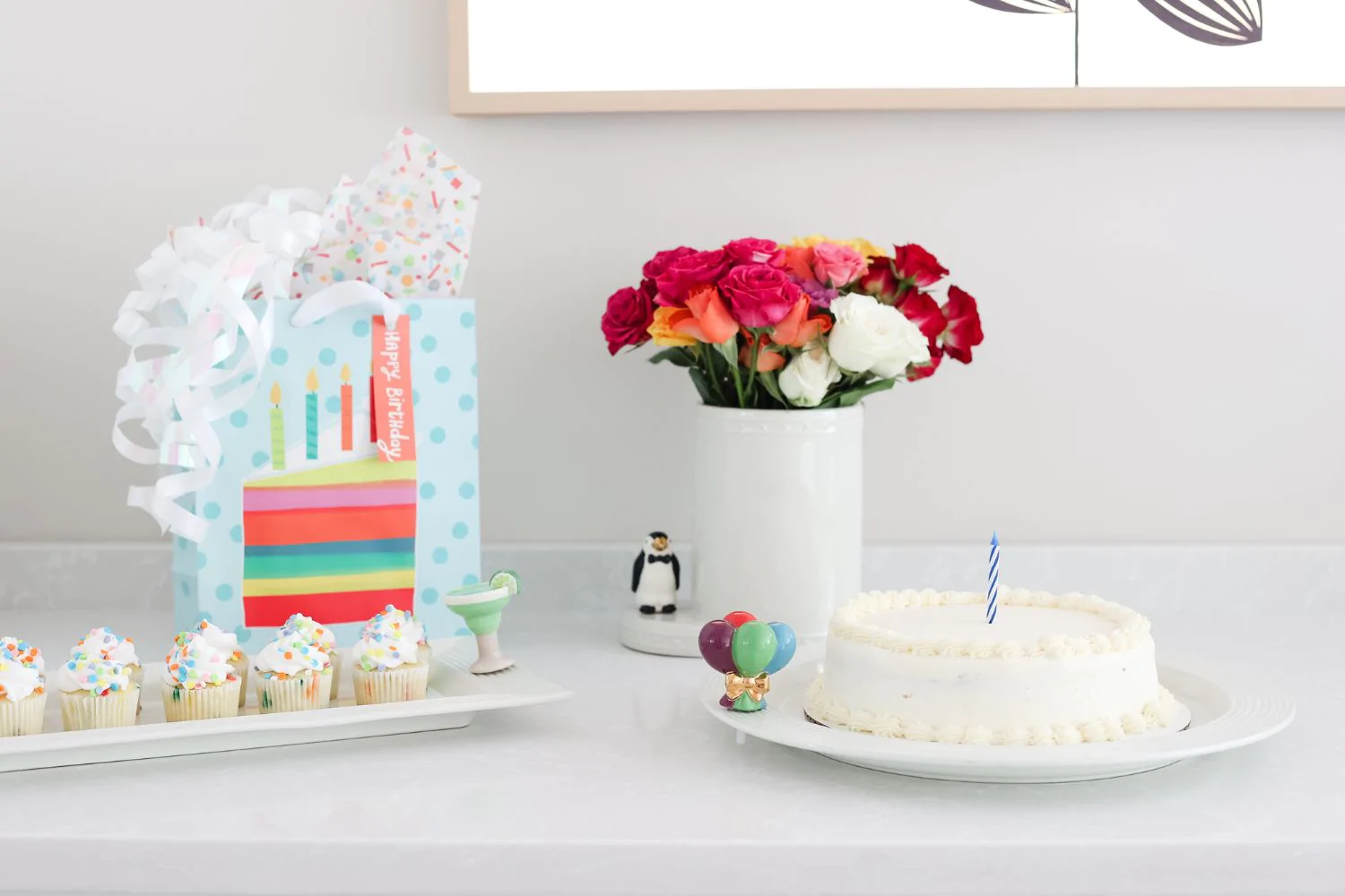 Nora Fleming Mini Tuxedo Penguin pictured with other minis attached to various items in a birthday scene